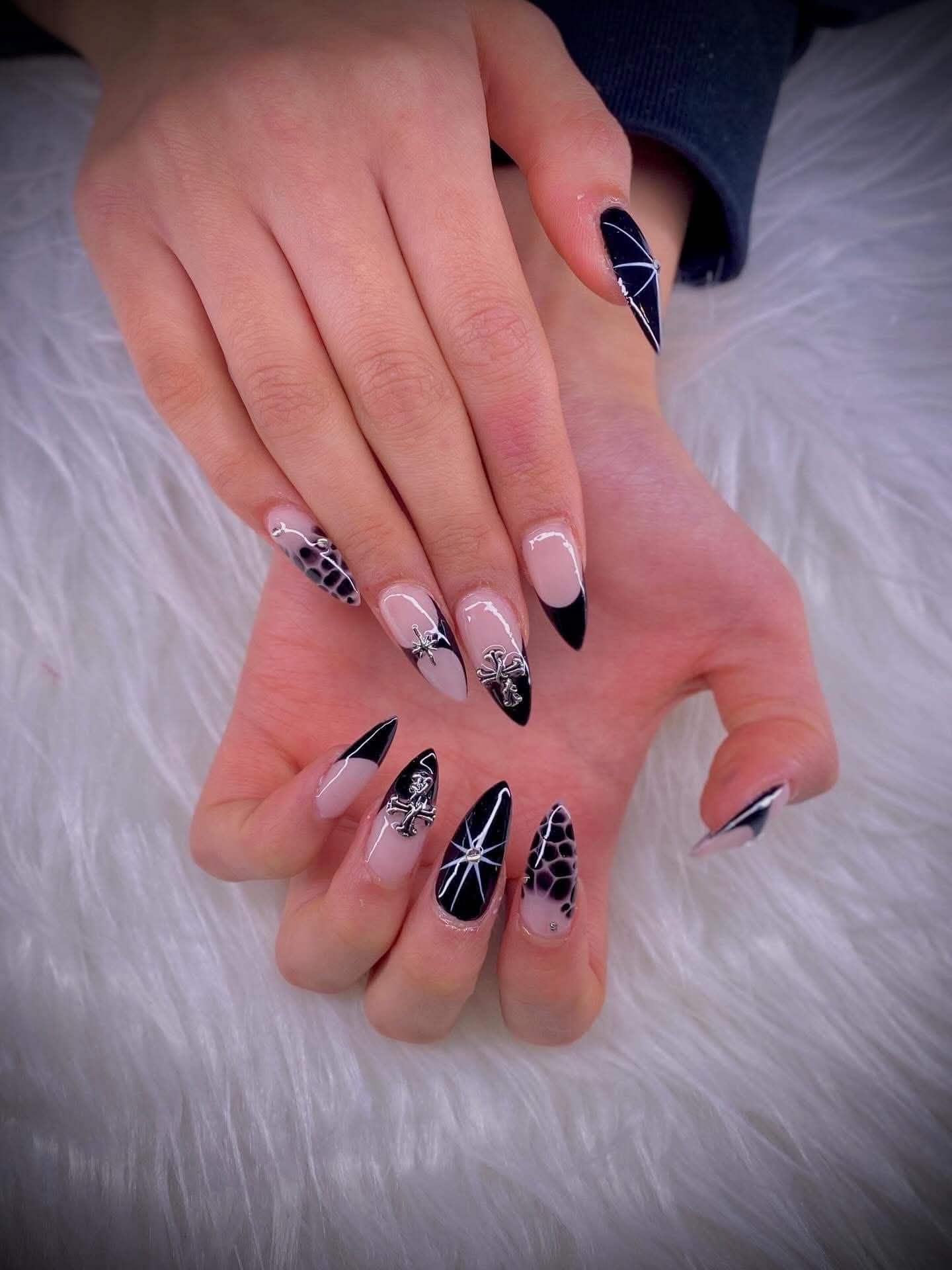 Stiletto nails with black tips, silver cross charms and web line work