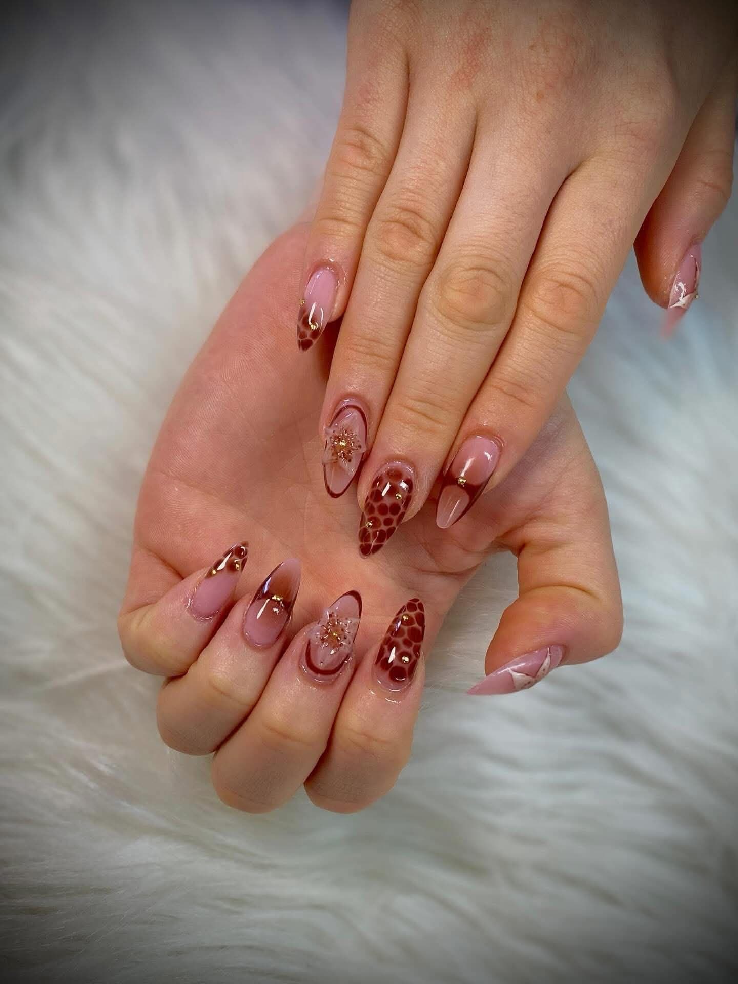 Almond nails in burgundy with snakeskin print, gold beads and a 3D flower