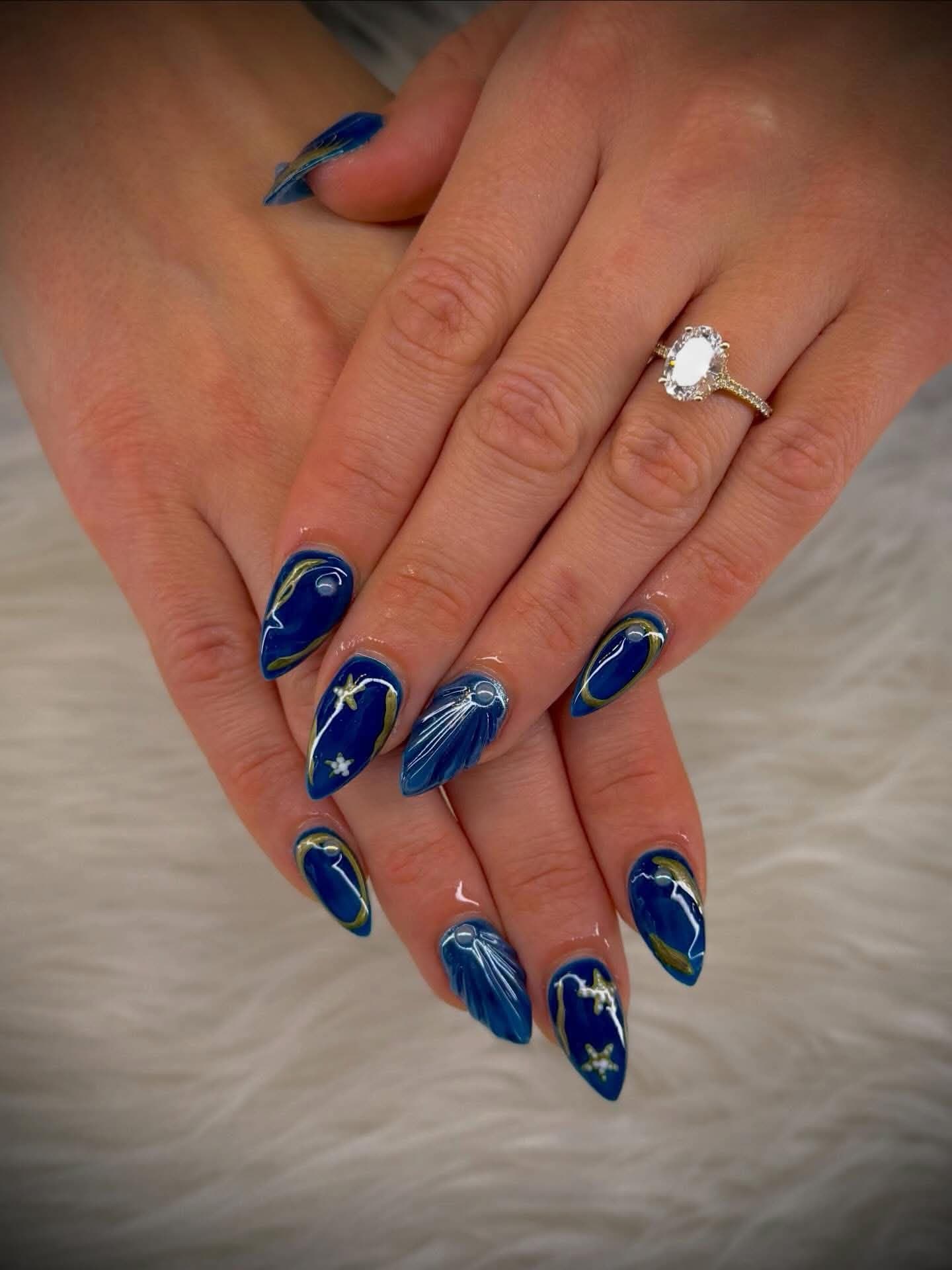 Navy almond nails outlined in gold with sculpted shells and starfish
