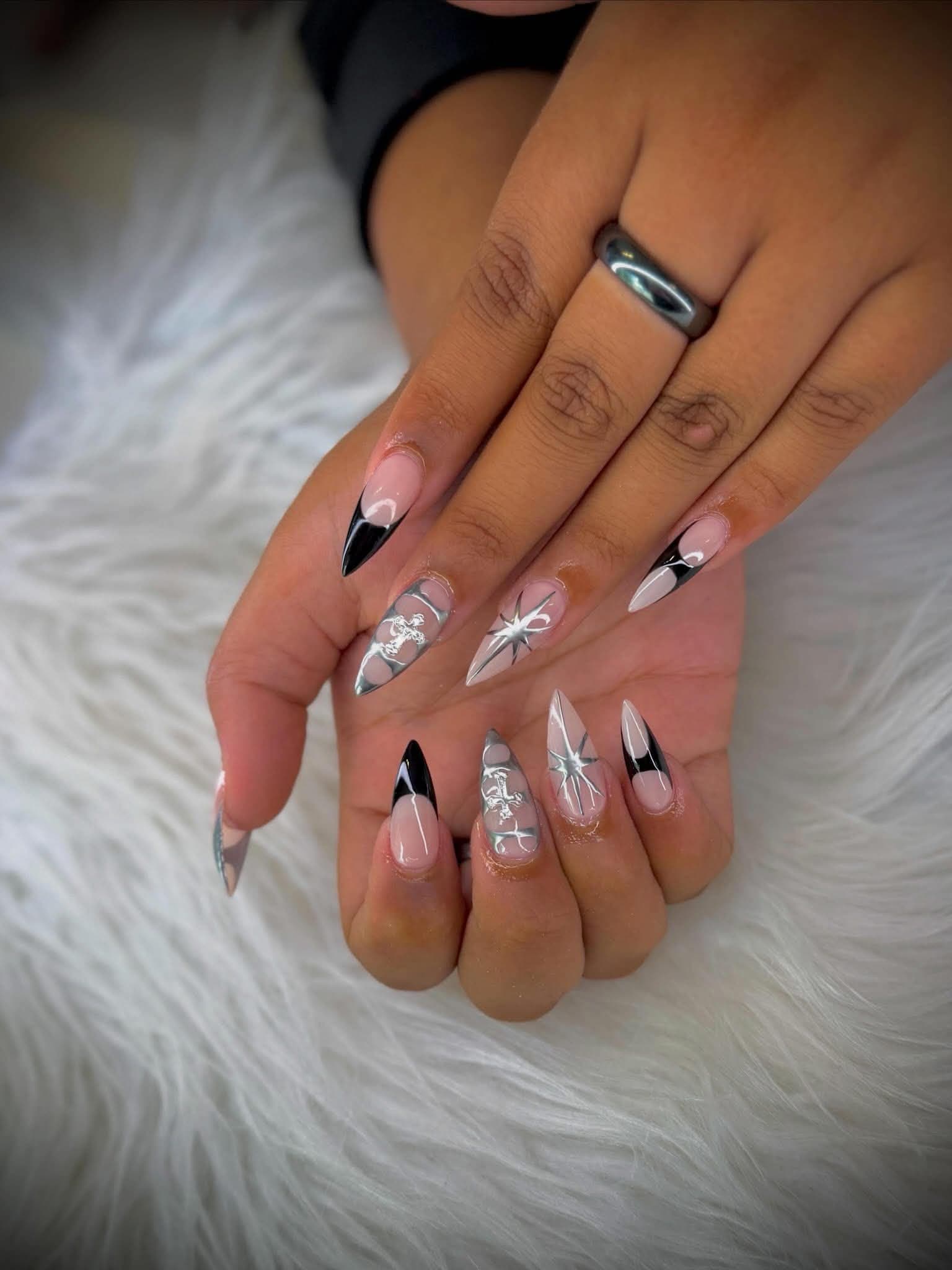 Stiletto nails in black and nude with silver chrome, cross charms and starbursts