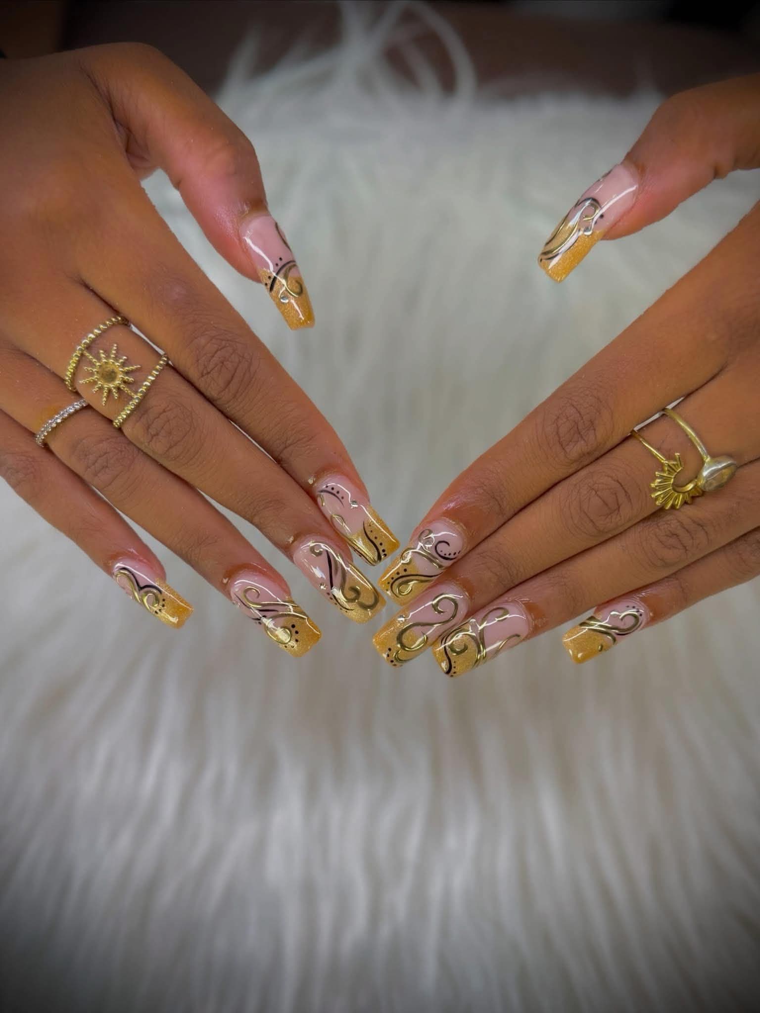 Long coffin nails with gold glitter tips and black and gold swirl line work