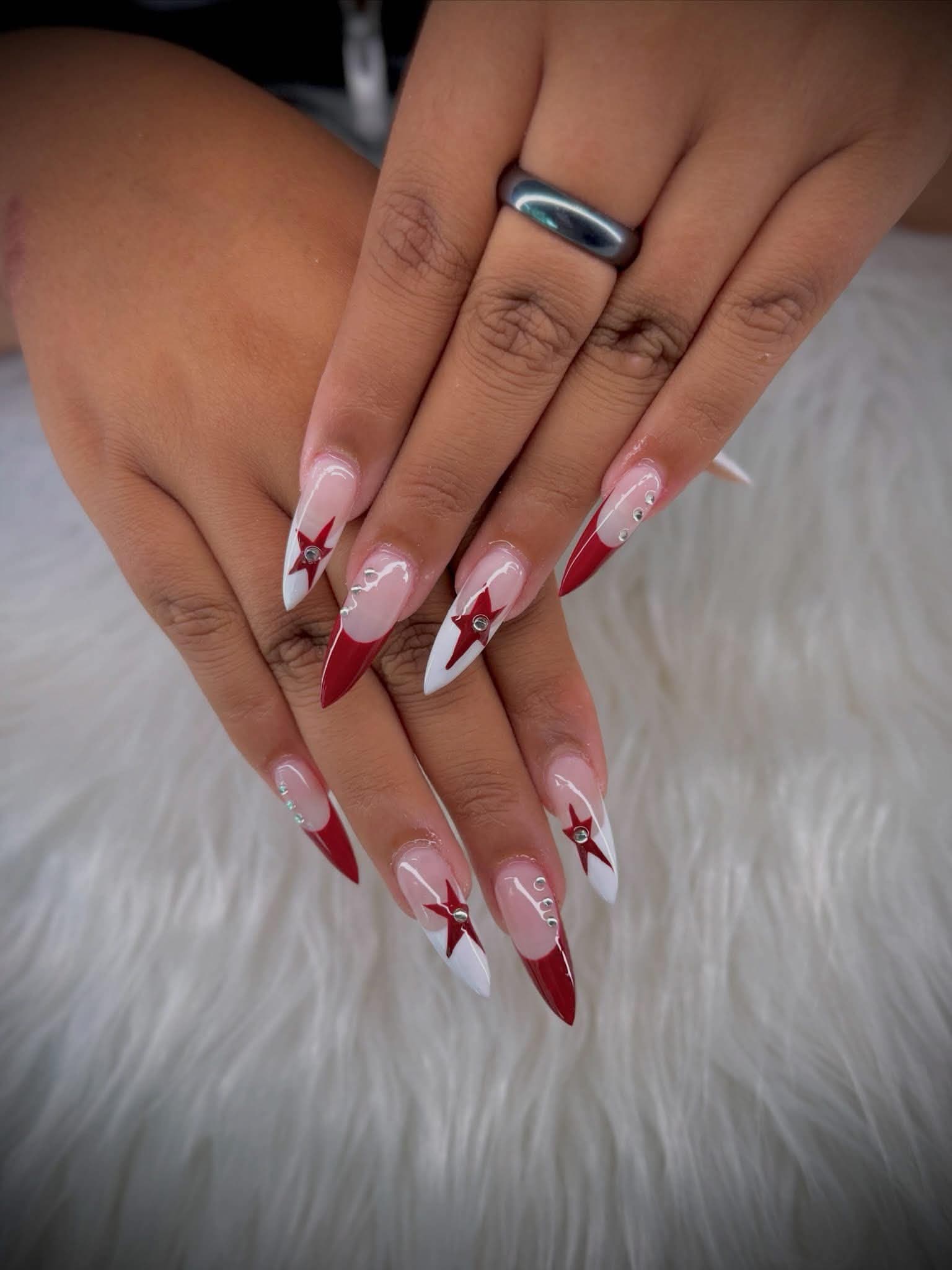 Stiletto nails with red and white french tips, painted stars and crystals